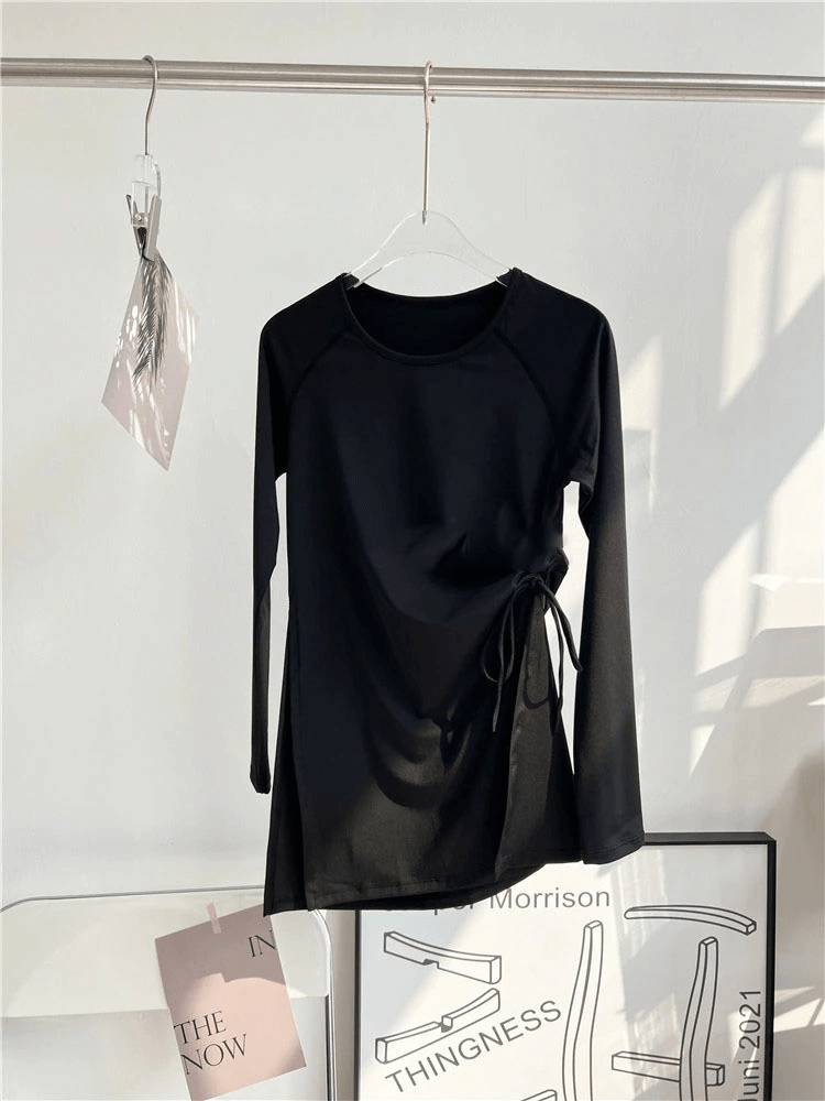 Black sports waist drawstring top with slits for women, hanging on a rack. Elastic fabric, full sleeves, perfect for fitness.